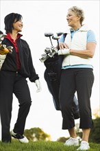 Women carrying golf clubs on golf course