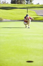 Caucasian woman planning putt on green at golf course