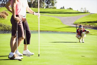 Women planning putt on green at golf course