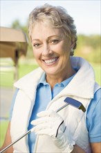 Caucasian woman holding putter on golf course