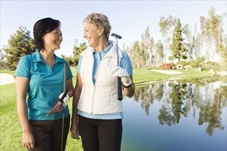 Women laughing on golf course near water hazard