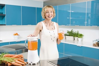 Caucasian woman juicing carrots in kitchen