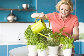 Caucasian woman watering plants in kitchen