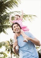 Caucasian father carrying baby daughter on shoulders
