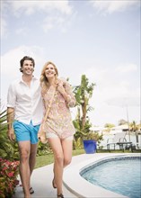 Caucasian couple walking near swimming pool