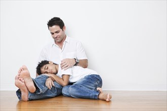 Mixed Race boy napping in lap of father on floor
