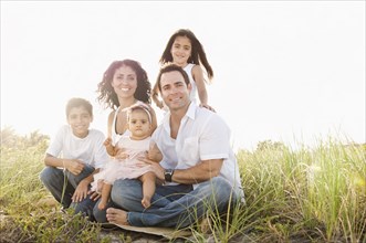 Portrait of Mixed Race family sitting in grass