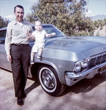 Caucasian father posing near car with baby son