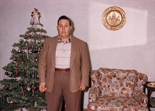 Serious Caucasian man posing near Christmas tree