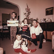 Caucasian father with son and daughters posing with Christmas gifts