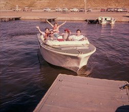 Portrait of smiling Caucasian family waving on boat near dock
