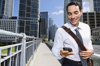 Hispanic businessman texting on cell phone in city