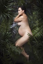 Naked Caucasian expectant mother laying in water