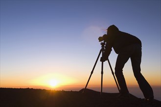 Silhouette of Mixed Race photographer with camera at sunset
