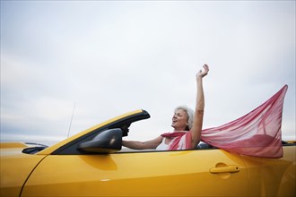 Caucasian woman driving yellow convertible