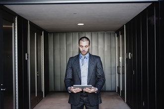 Businessman using digital tablet in corridor