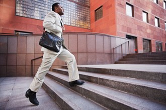 African American businessman running up steps