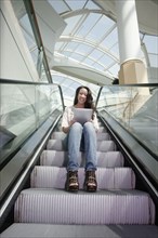 Woman on escalator using digital tablet