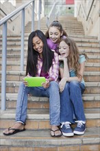 Girls using digital tablet on staircase