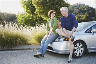 Caucasian couple leaning on car