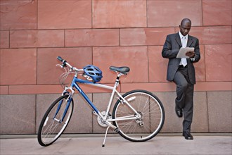 Businessman using digital tablet near bicycle