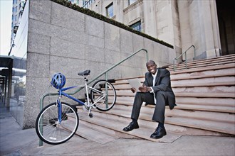 Businessman sitting on stairs using digital tablet