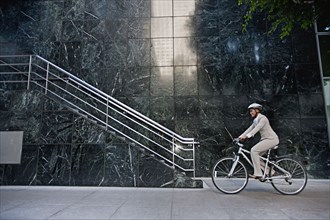 Businesswoman riding bicycle on sidewalk