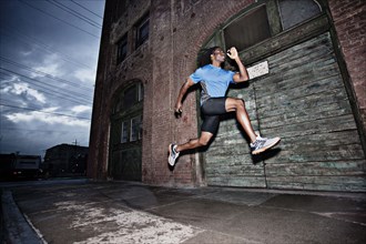 Male athlete running on sidewalk