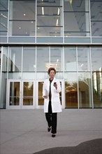 Doctor walking and text messaging on cell phone