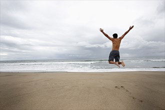 Young man jumping for joy on beach