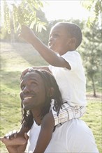 African American man carrying son on shoulders