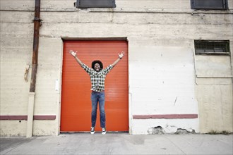 Excited Black man jumping on sidewalk