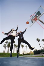 Businessmen playing basketball outdoors