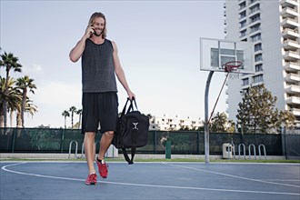 Caucasian man on basketball court talking on cell phone