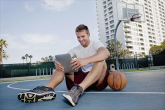 Caucasian man using digital tablet on basketball court