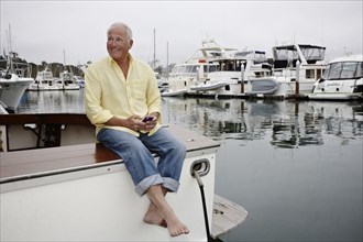 Man sitting on boat text messaging on cell phone