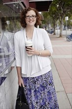 Mixed race woman drinking coffee on sidewalk