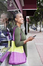 Black woman text messaging on sidewalk