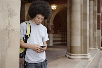 Student with afro text messaging on cell phone