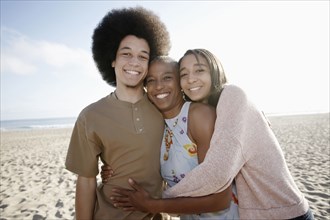 Mother and children hugging on beach