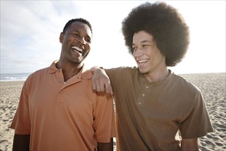 Father and son standing together on beach