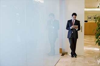Hispanic businessman using digital tablet in office corridor