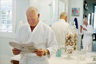 Caucasian man reading newspaper in bathroom