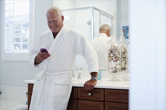 Caucasian man in robe using cell phone