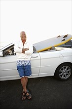 Caucasian man standing with car and paddleboard