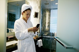Mixed race woman text messaging on cell phone in bathroom