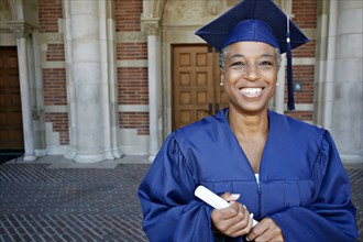 Smiling Black woman holding graduation diploma