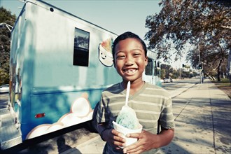 Mixed race boy eating ice cream from truck