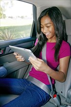 Mixed race girl using digital tablet in car