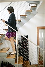 Mixed race businesswoman climbing staircase